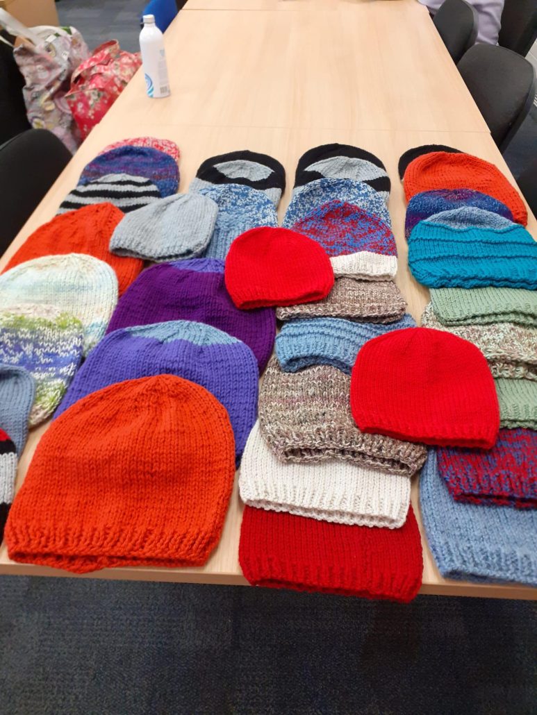 Hand knitted hats in many colours laying artistically on a table.