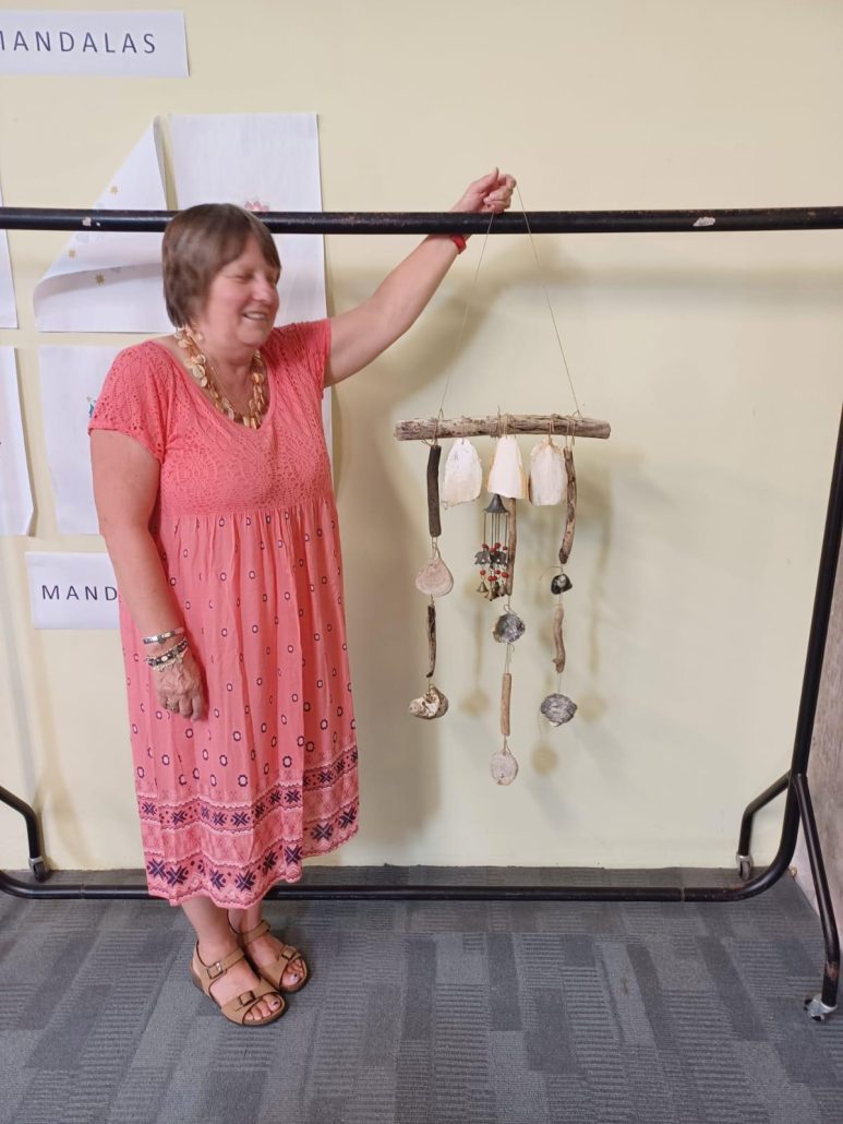 Lady holding mobile made of sea shells.